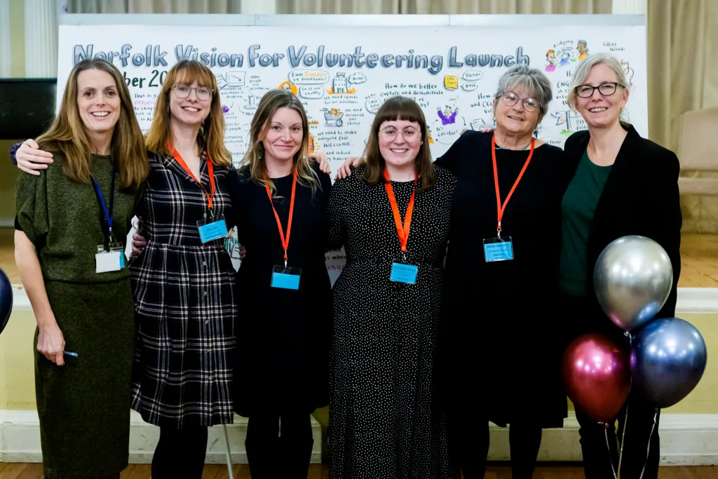 Group of staff in front of the vision for volunteering graphic