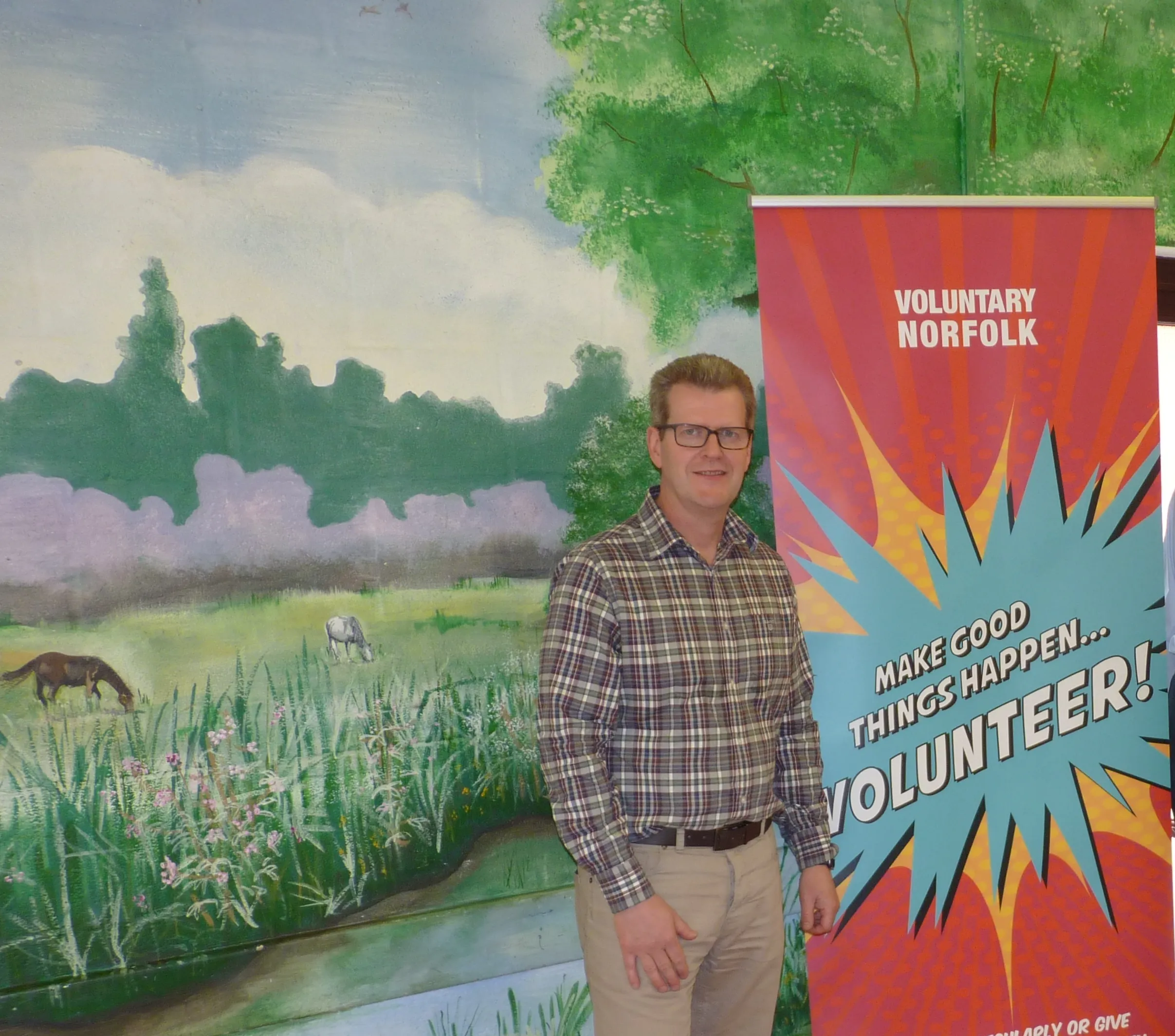 John Archibald in front of Voluntary Norfolk banner