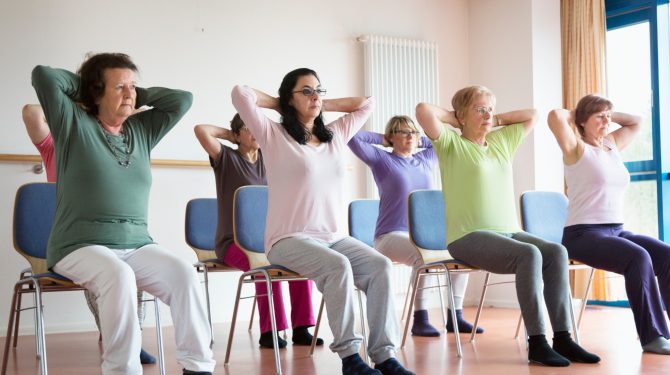 group of people sitting down taking part in chair yoga