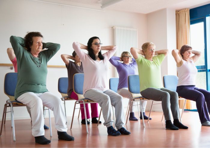 group of people sitting down taking part in chair yoga
