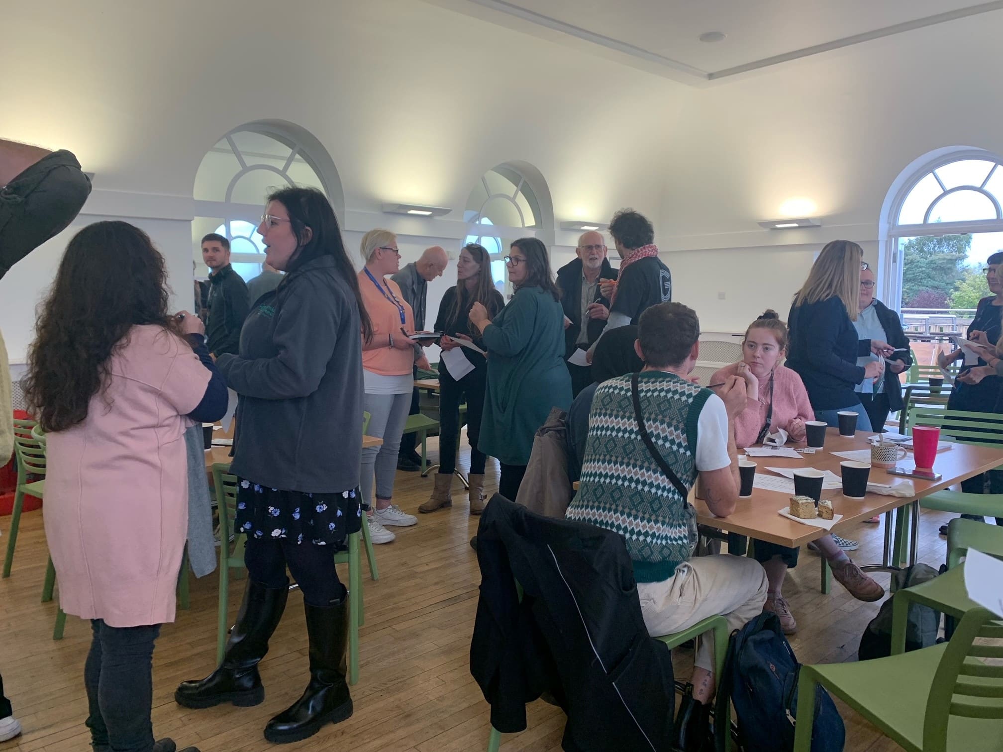 Room full of people chatting over coffee and cake.